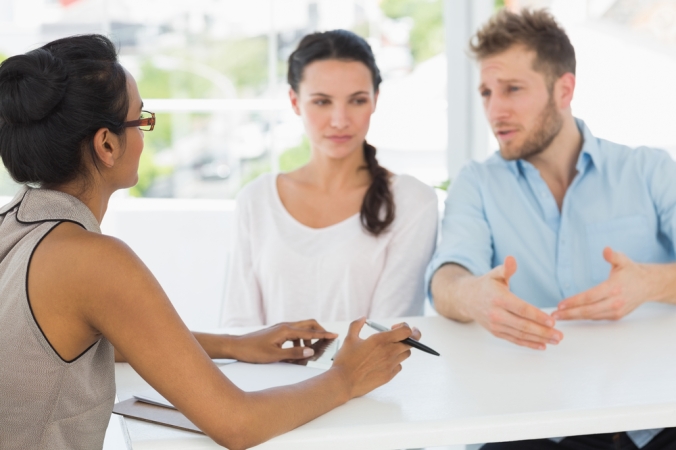 Therapist speaking with couple sitting at desk in therapists office